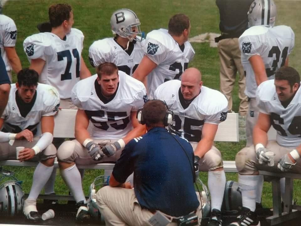 Butler defenders on the sideline bench listening to a coach in a headset, number 55 in the center.