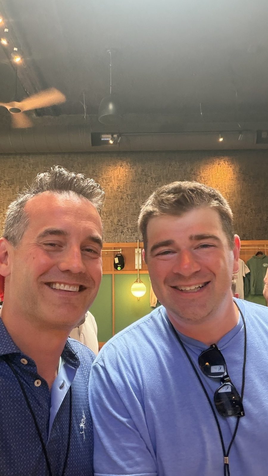 Two men in collared shirts and lanyards smiling for a selfie.