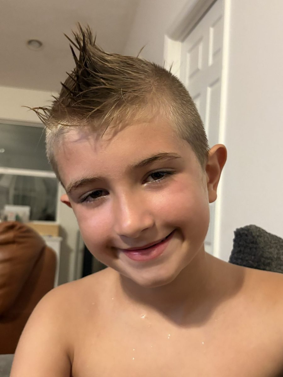 A smiling boy with a spiky mohawk haircut.