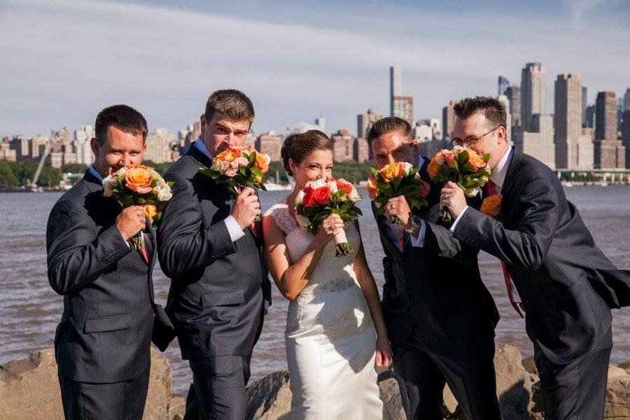 A wedding party holding bouquets in front of the New York skyline across the Hudson River.