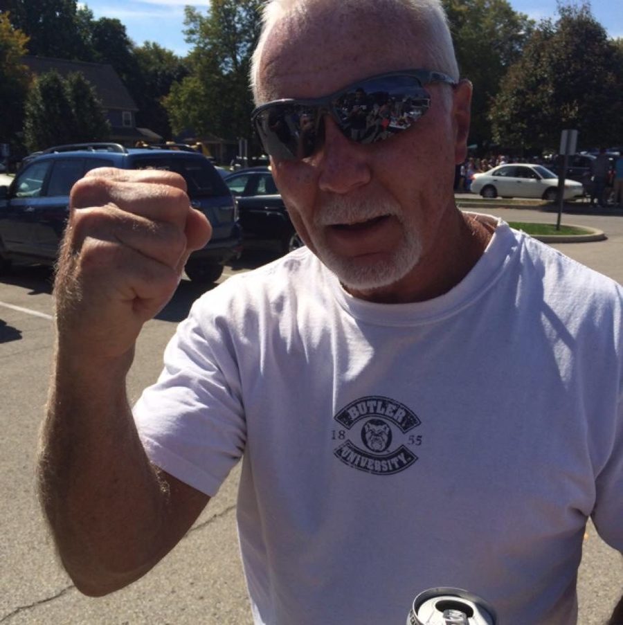 John Haynes in sunglasses and a Butler shirt raising a fist at a tailgate.