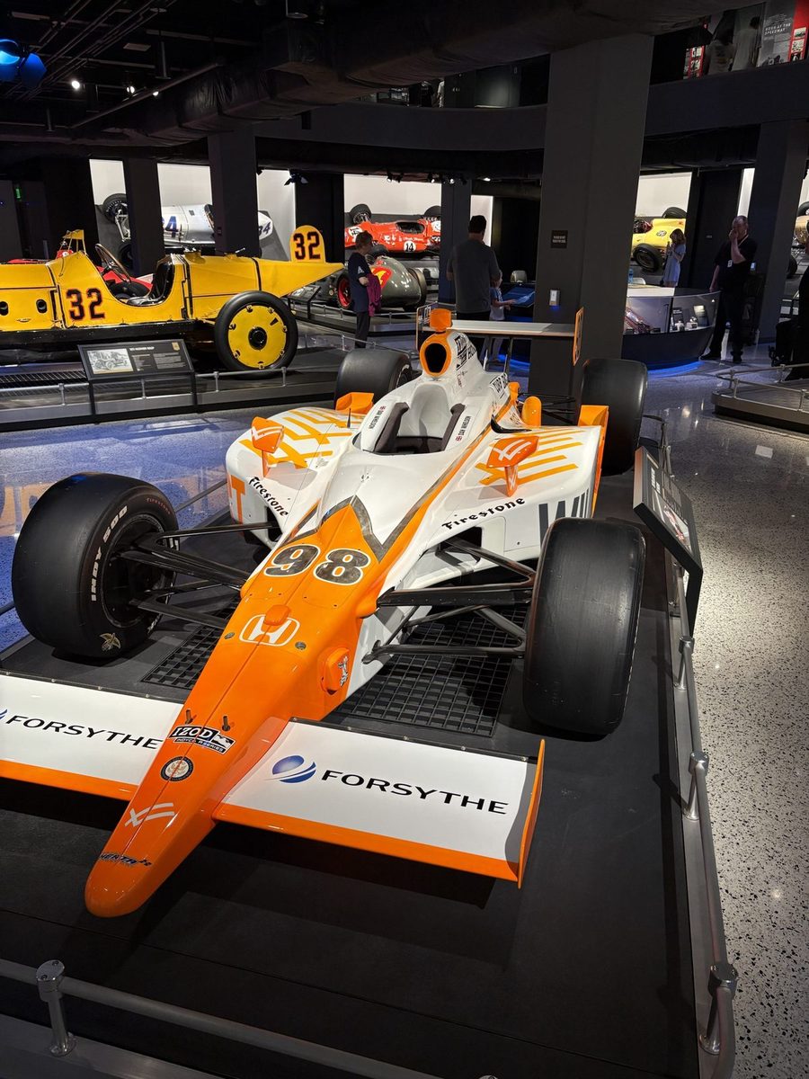 An orange and white IndyCar number 98 on display at the Indianapolis Motor Speedway Museum.
