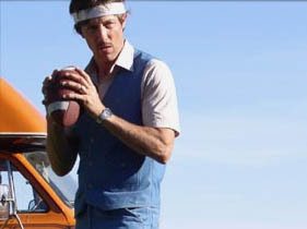 David McMahon in a headband and vest, cocking a football to throw